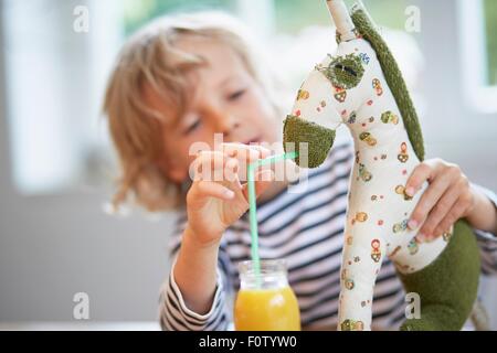 Ragazzo giovane fingendo di bevanda di alimentazione al giocattolo morbido Foto Stock