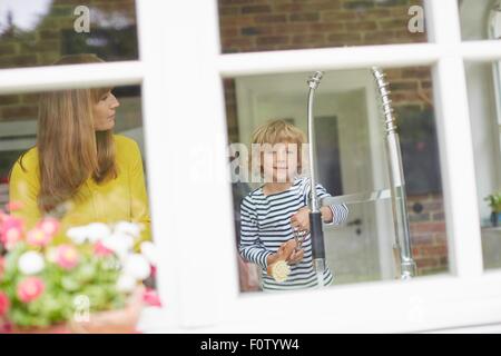 Madre e figlio facendo il lavaggio fino, vista attraverso la finestra Foto Stock