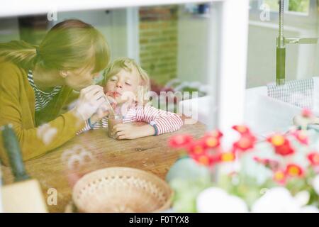 Madre e figlio condividendo un drink insieme, vista attraverso la finestra Foto Stock