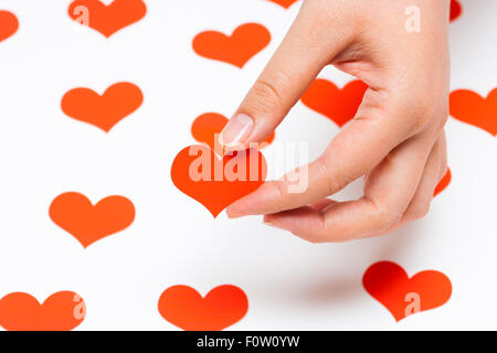 Carta rossa cuore in mano di donna con cuori su sfondo bianco Foto Stock