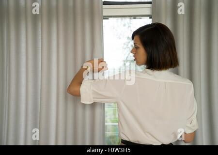 Imprenditrice guardando orologio da polso nella parte anteriore della finestra Foto Stock