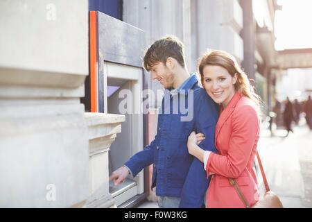 Giovane prelevare denaro da street bancomat, London, Regno Unito Foto Stock