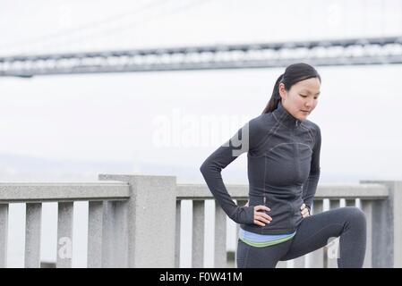 Femmina stretching runner sul ponte, San Francisco, California Foto Stock