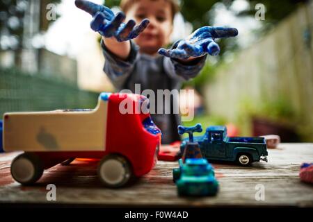 Ragazzo giocando con i camion giocattolo e acquerello Foto Stock