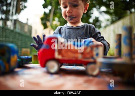 Ragazzo giocando con i camion giocattolo e acquerello Foto Stock