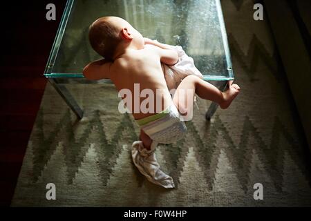 Ragazzo semi-salendo sul tavolo di vetro Foto Stock