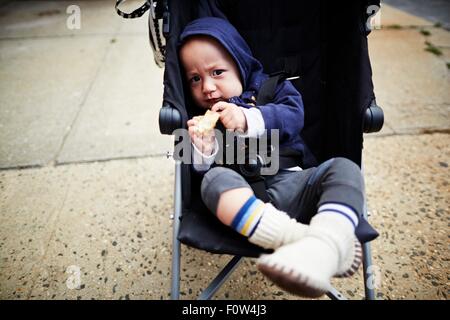 Baby boy holding cookie nel carrello Foto Stock