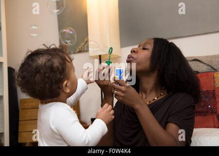 Metà donna adulto e bambino figlia soffiare bolle Foto Stock