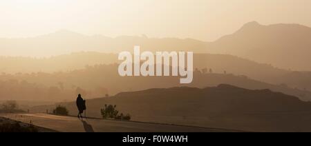 Vista posteriore del senior uomo in abbigliamento tradizionale che guarda oltre il paesaggio al tramonto, Etiopia, Africa Foto Stock