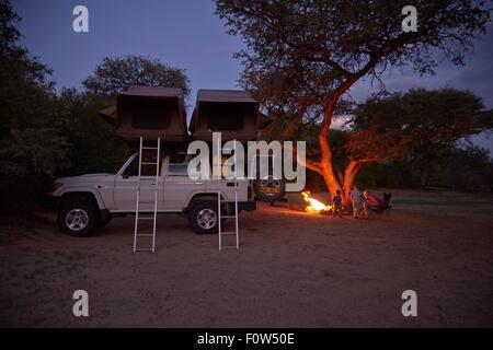 Off road veicolo parcheggiato, famiglia seduti intorno al falò, Purros, Kaokoland, Namibia Foto Stock