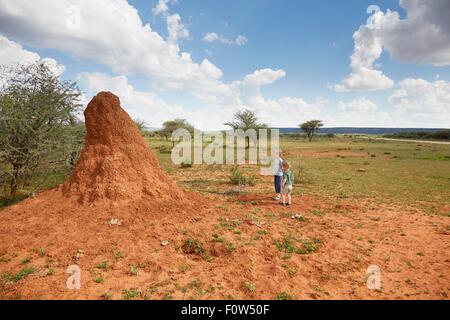 Due giovani ragazzi guardando termite hill, Opuwo, Kaokoland, Namibia Foto Stock