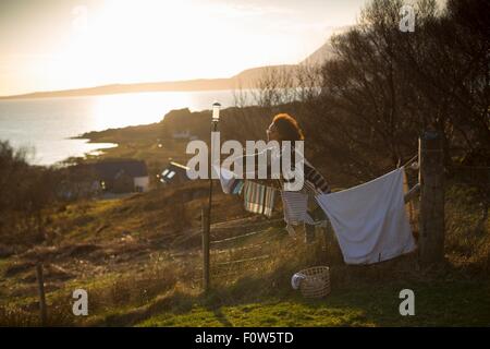 Donna appendere fuori il lavaggio in giardino, Tokavaig, Isola di Skye in Scozia Foto Stock