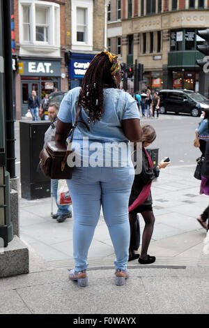 Vista posteriore del sovrappeso attraente donna nera in stretto jeans denim su una strada di città di Londra, KATHY DEWITT Foto Stock