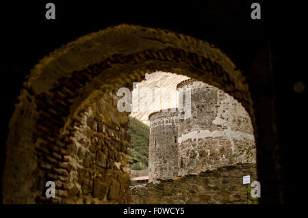 Esplorando le antiche fortificazioni in pietra annidate in un paesaggio montuoso durante la luce del tardo pomeriggio Foto Stock