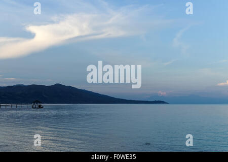 Una mattina blu in spiaggia. Ci sono un paio di persone intorno, barche sono a sinistra sulla riva, e l'acqua si è ritirato verso l'esterno Foto Stock