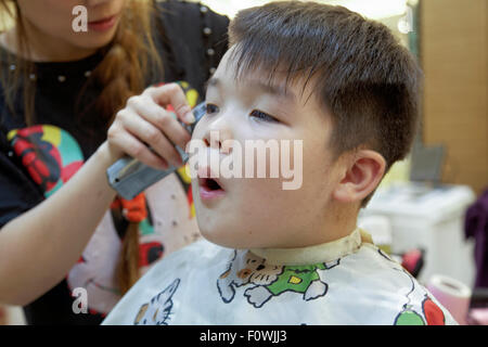 A 7 anno di età razza mista ragazzo di ottenere un taglio di capelli Foto Stock