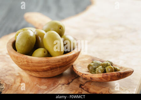 Verde enorme olive e capperi sulla tavola di legno Foto Stock
