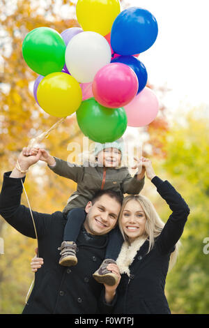 Felice famiglia con bambino e aria-palloncini, gita in autunno park Foto Stock