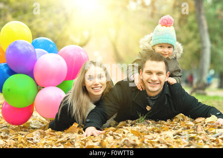 Felice famiglia con bambino e aria-palloncini, gita in autunno park Foto Stock