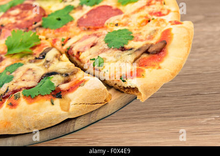 Home pizza fatta a bordo al tavolo di legno Foto Stock