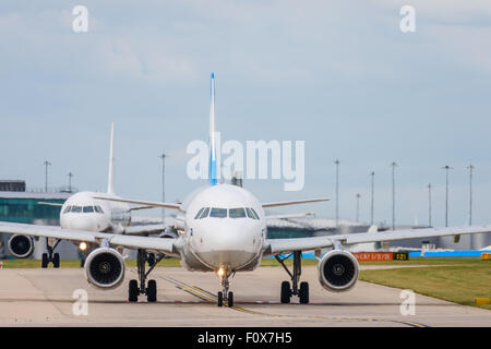 Un Airbus A320-200 piano del bagno turco aria operatore Freebird taxi per la pista dell'aeroporto di Manchester seguita da un monarca A321 Foto Stock