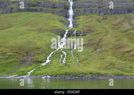 L'Islanda, Westfjords, Jokulflrdir, Lonagfjordur Riserva Naturale (66°16'33' N 22°37'15" W). Fiordo remoto cascata. Foto Stock