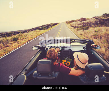 Felice Coppia giovane la guida lungo la strada di campagna nel convertibile al tramonto Foto Stock