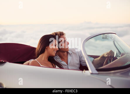 Romantico giovane coppia attraente guardare il tramonto in Classic Vintage auto sportive Foto Stock