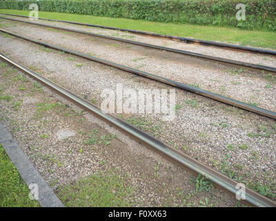 Piegatura di rotaie del tram. Sulla strada di una soleggiata giornata estiva, erba verde. Foto Stock