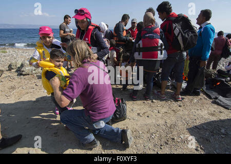 Lesbo, Grecia. 23 Ago, 2015. Eric Kempson, un British Vita in Grecia aiuta un bambino togliersi il giubbotto di salvataggio. Circa trecento rifugiati dalla Siria ha raggiunto le coste del Nordest dell isola di Lesbo attraversato dalla Turchia in un mare agitato. Credito: Nikolas Georgiou/ZUMA filo/Alamy Live News Foto Stock