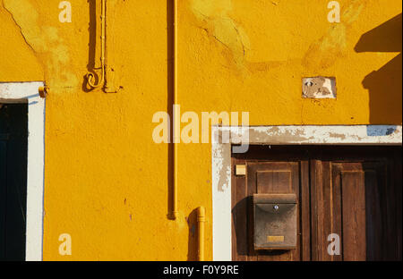 Parete di colore arancione e la vecchia cassetta postale sulla porta di legno Burano Laguna di Venezia Veneto Italia Europa Foto Stock