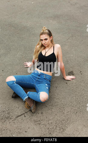 Robusto ragazza seduta gambe incrociate sul pavimento di skate park. Foto Stock