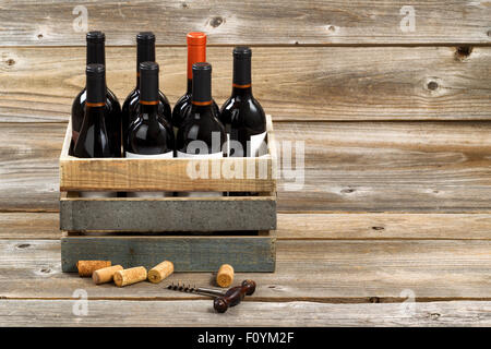 Bottiglie di vino rosso in casse di legno con il vecchio cavatappi e tappi utilizzati su rustiche tavole di legno. Foto Stock