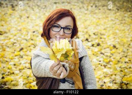 Giovane donna rosso giallo con foglie di autunno. Tema stagionale. Foto Stock