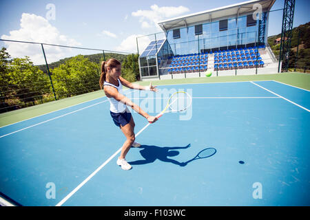 Femmina giocatore di tennis di eseguire un drop shot su una bella corte blu Foto Stock