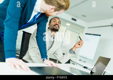 Un nero giovane con dreadlocks e un giovane bello dai capelli rossi imprenditore a discutere di grafica difetti di progettazione Foto Stock