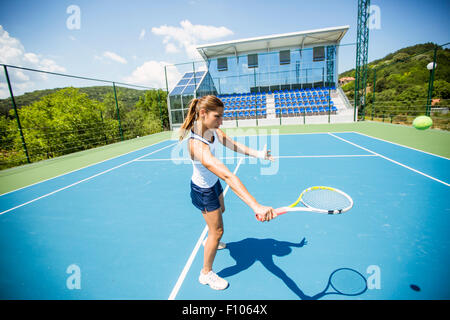 Femmina giocatore di tennis di eseguire un drop shot su una bella corte blu Foto Stock