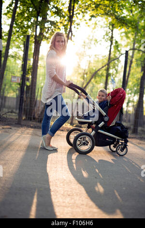 La madre del bambino a piedi in una carrozzina nel parco Foto Stock