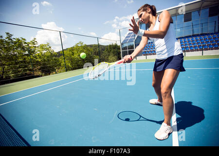 Femmina giocatore di tennis di eseguire un drop shot su una bella corte blu Foto Stock