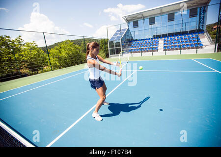 Femmina giocatore di tennis di eseguire un drop shot su una bella corte blu Foto Stock