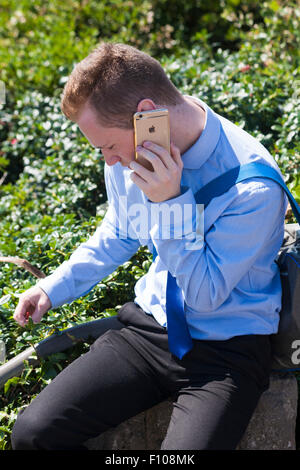 Giovane uomo che indossa una camicia blu con iphone oro con logo Apple a Bournemouth, Dorset UK, ad agosto Foto Stock