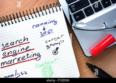 Blocco note con le parole il search engine marketing su uno sfondo di legno Foto Stock