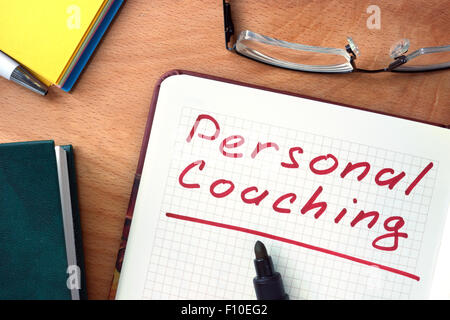 Blocco note con il personal coaching su office tavolo in legno. Foto Stock