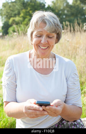 La vecchiaia donna utilizzando smart phone Foto Stock