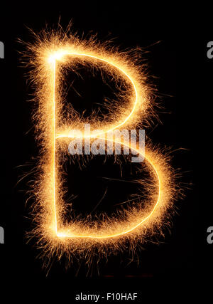 " B " lettera estratta con brillantini bengali isolati su sfondo nero Foto Stock