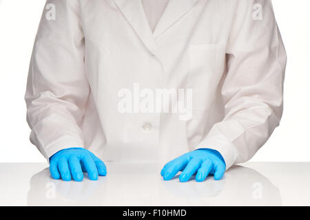 Donne medico le mani in guanti blu recante sul tavolo bianco su sfondo bianco Foto Stock