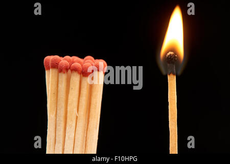 Gruppo di legno rosso corrisponde a piedi con Fiammifero bruciato, isolato su sfondo nero Foto Stock