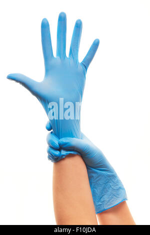 Close up medico donna di mettere le mani su blu sterilizzato guanti chirurgici contro uno sfondo bianco Foto Stock