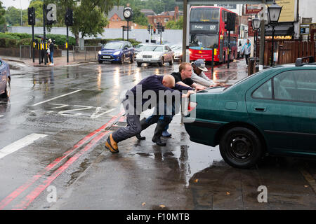 Purley, Londra, UK, 24 agosto 2015. Tre gli astanti aiutare un filamento auto fuori acqua di inondazione. Un giallo allarme alluvione per Londra è stato rilasciato dal Met Office. Una quindicina di giorni di pioggia è previsto a cadere in 24 ore. Credito: Dave Stevenson/Alamy Live News Foto Stock