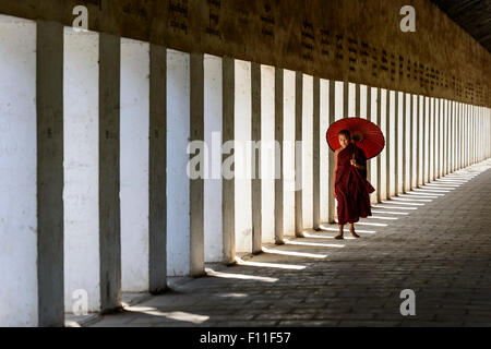 Asian monaco-in-formazione che porta ombrellone in corridoio Foto Stock